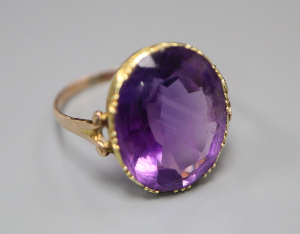 A 19th century gold and amethyst dress ring (tests as 9ct), with collet setting and carved scrolled shoulders